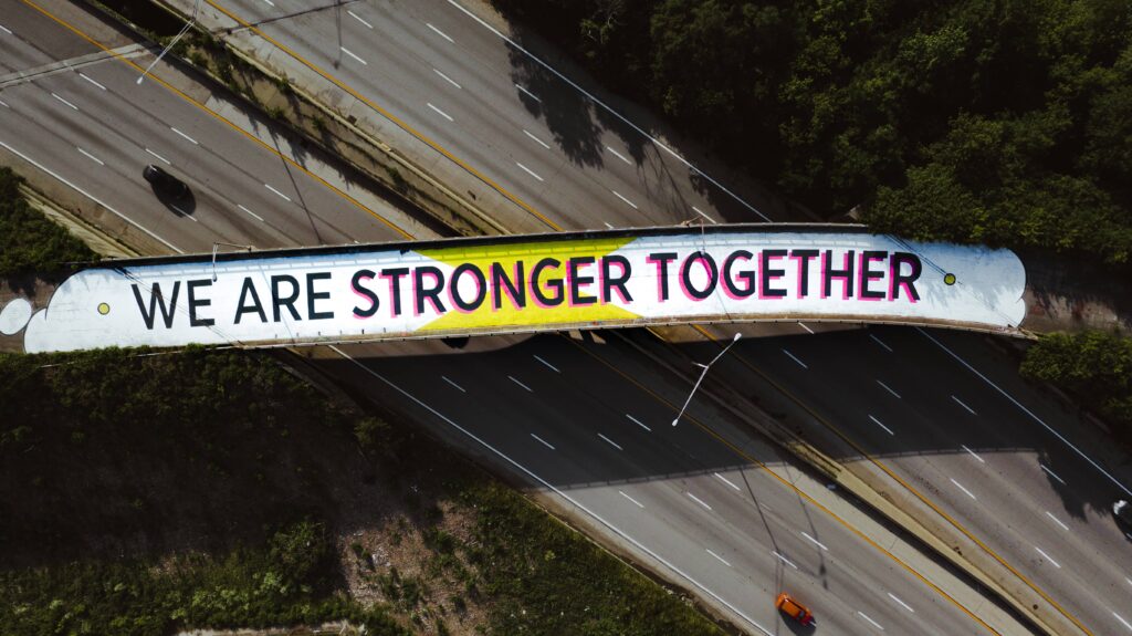 Bird's eye view of a bridge covered in street art that reads 'we are stronger together', showing creative dissemination of a powerful message.