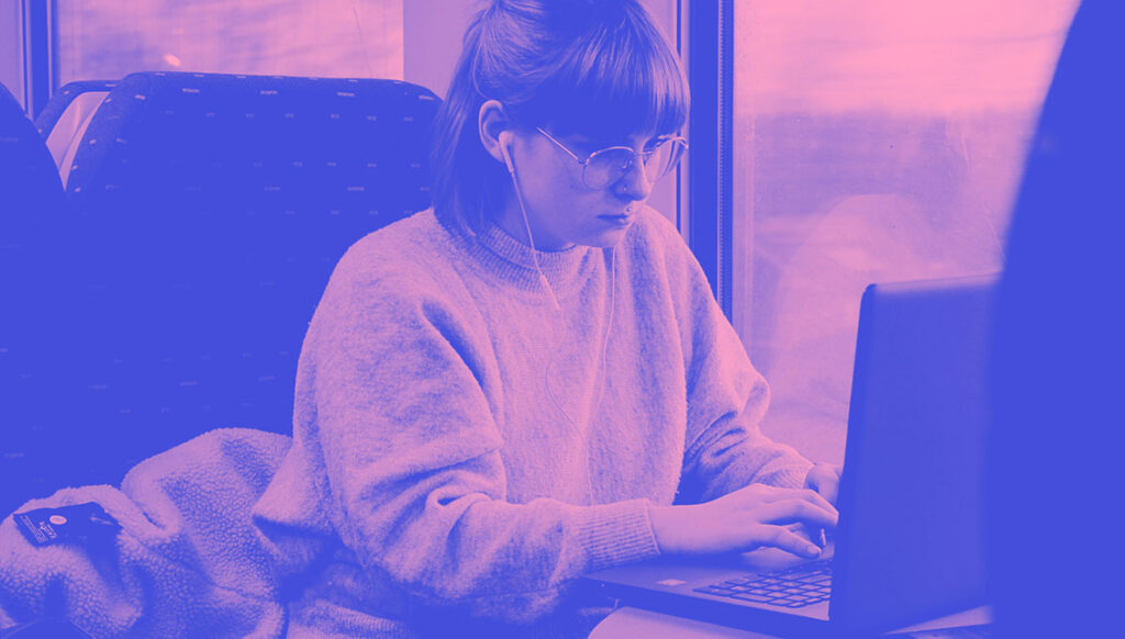 University student working on a laptop whilst travelling on the train