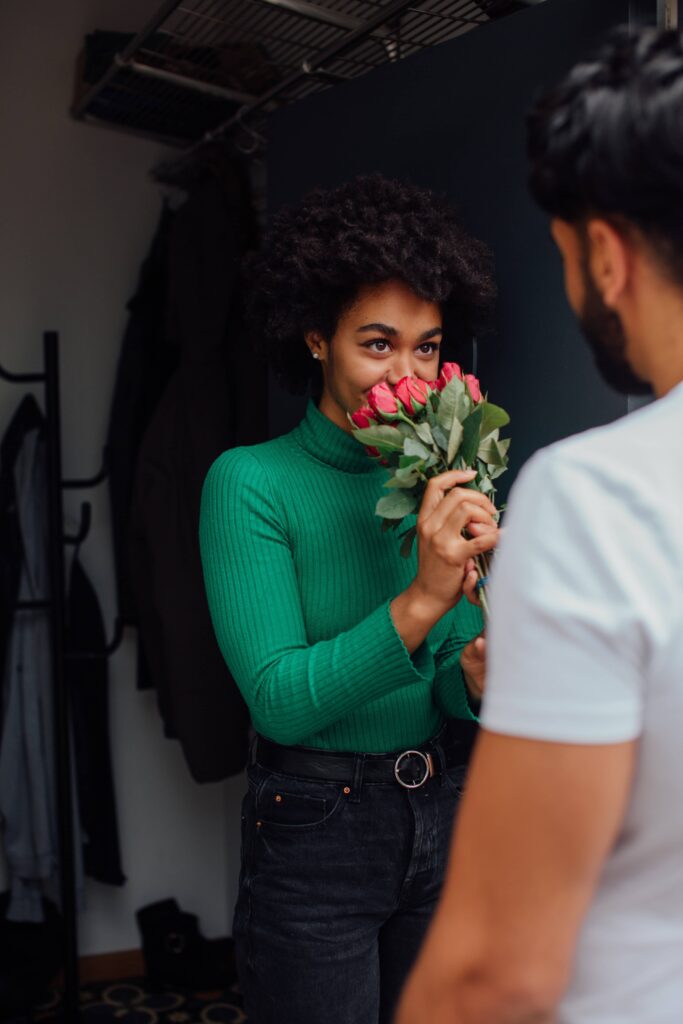 woman smelling a bunch of roses and smiling at the man who gave them to her