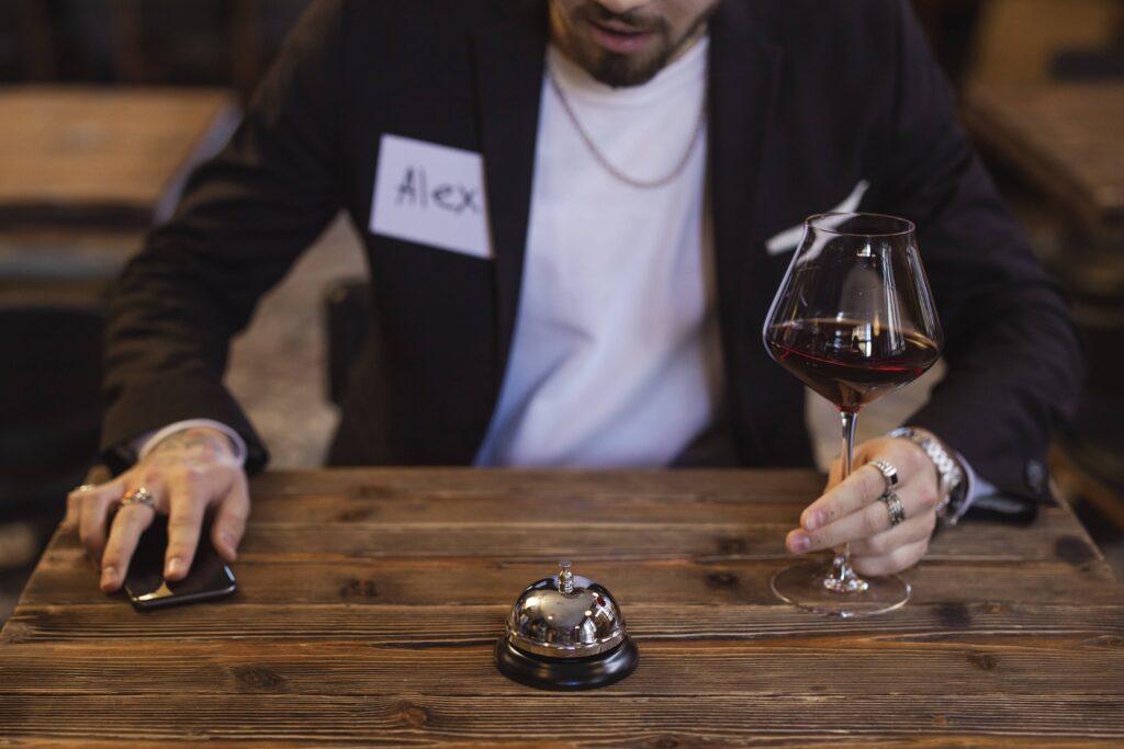 man with a name-sticker on holding a glass of wine at a speed-dating event.