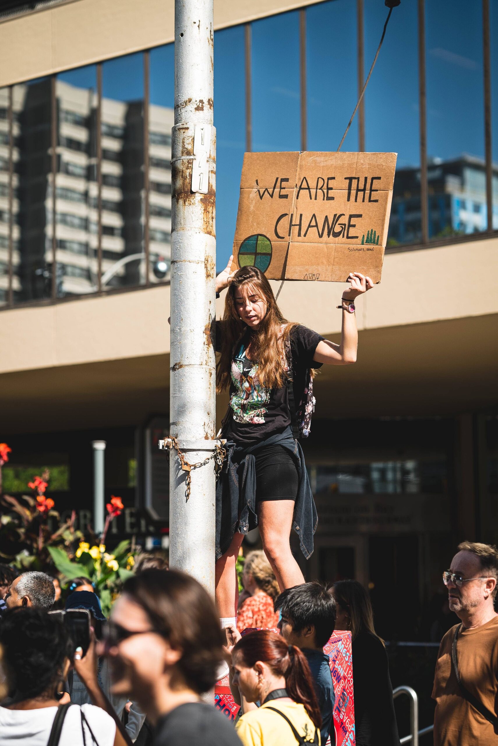 Gen Z climate protestor holds sign that reads 'We Are The Change'